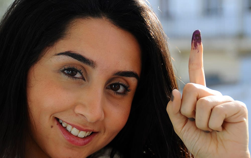 Tunisian voter Dina Ghlisse displays her finger with the indelible ink mark after voting in La Marsa, on the outskirts of Tunis, Tunisia.