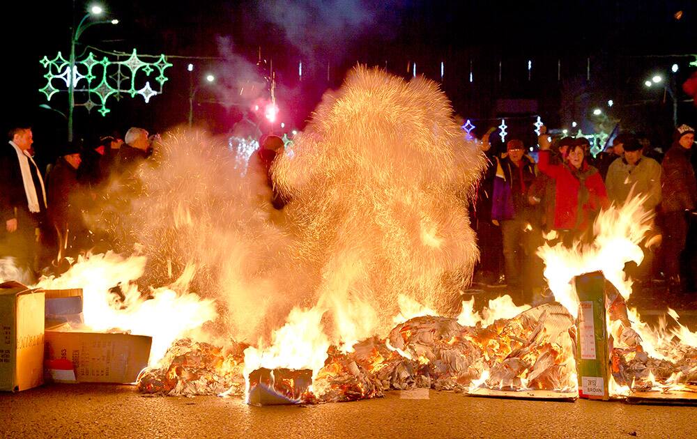 Romanians shout anti-Communist slogans by burning piles of cardboard boxes, during a reenactment of the 1989 uprising in Bucharest, Romania.