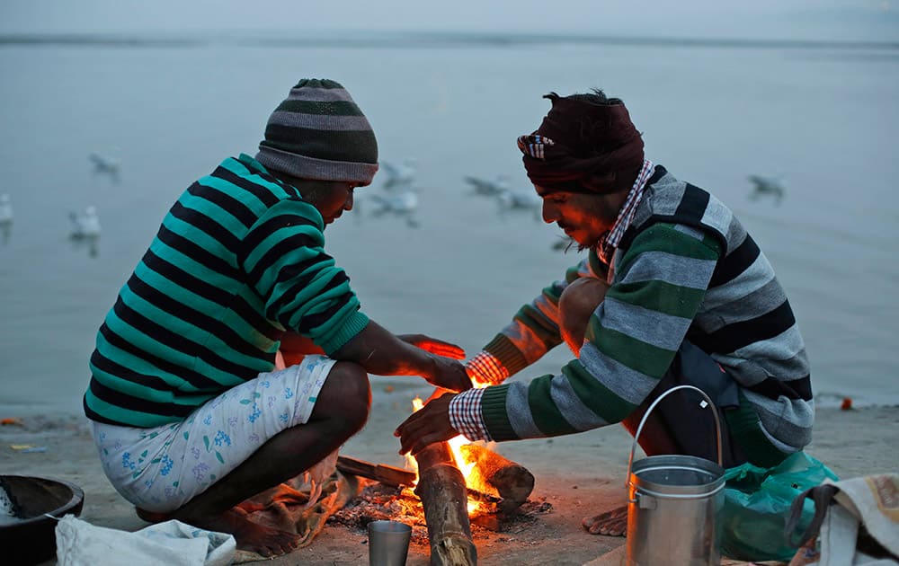 Indian street vendors keep warm around a bonfire on a cold evening on the banks of the River Ganges in Allahabad.