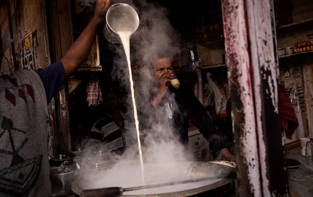 An Indian man pours milk into a huge pot to prepare tea at a roadside stall in old parts of New Delhi.