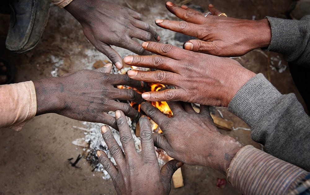 Indian men warm their hands near a bonfire on a cold and foggy morning in Allahabad.