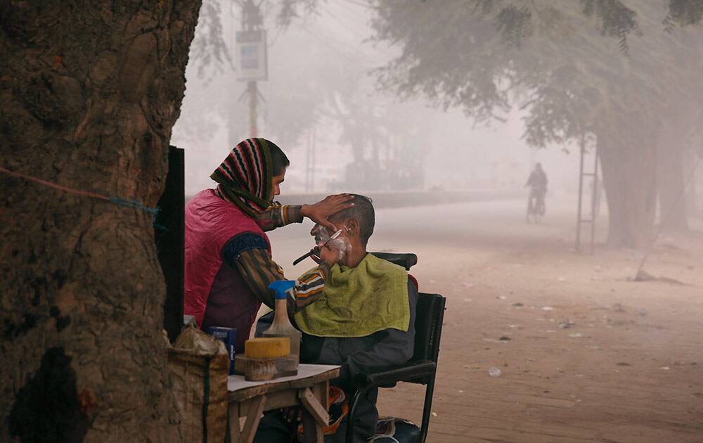 An Indian man gets a shave on a cold morning, at Allahabad, India, Monday.