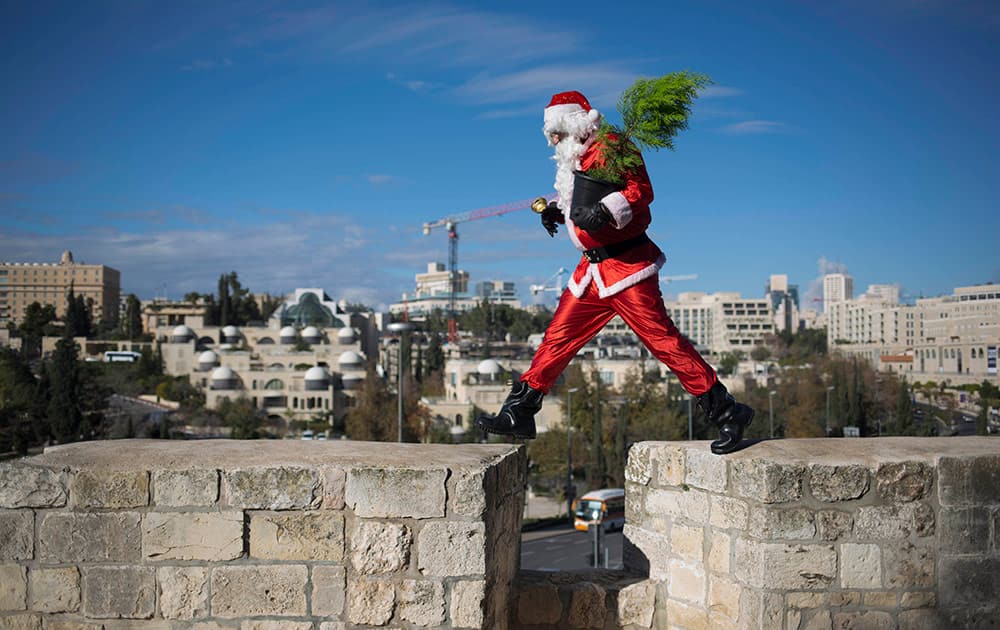 A man dressed as Santa Claus walks on the wall of the Old City in Jerusalem Monday.