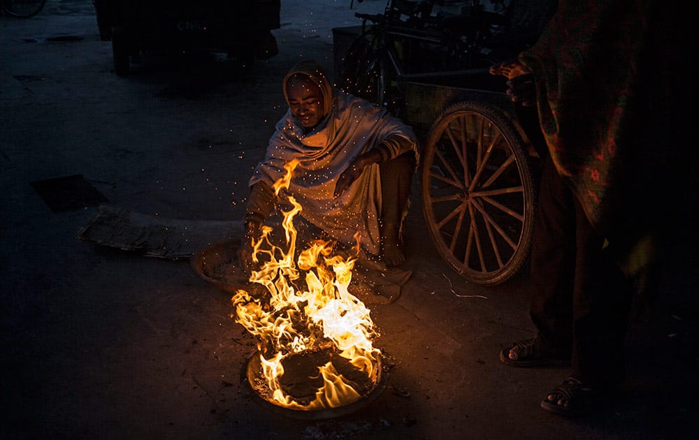 Indian men stay warm near a fire in New Delhi, India, Monday.