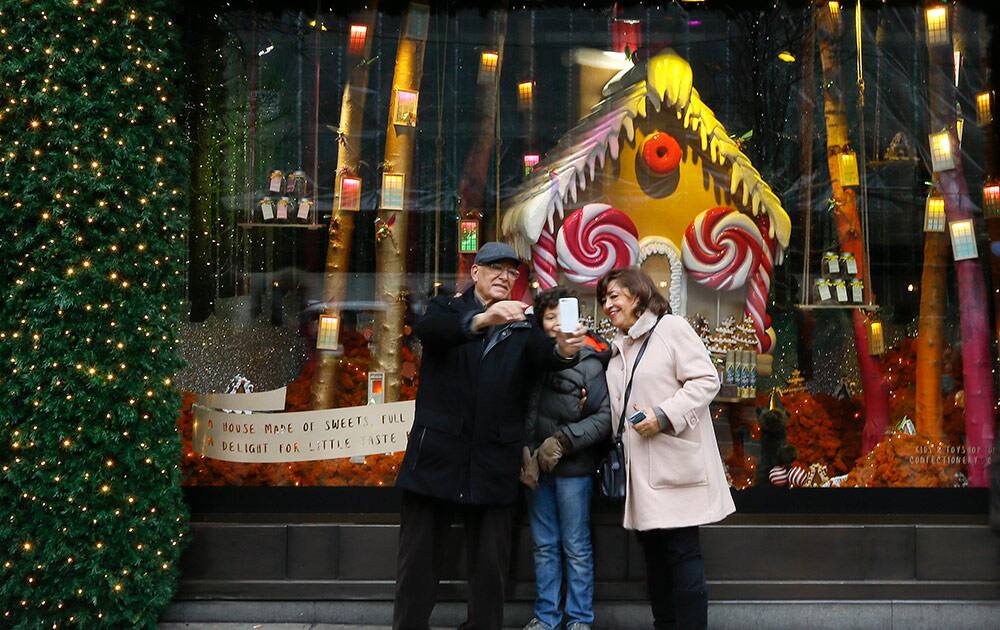 People take a photograph in front of a festive window display on Oxford Street in London, Monday.