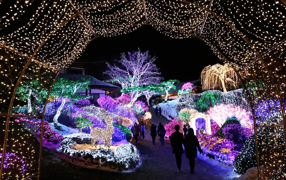 Visitors are silhouetted with decorated lights on trees to celebrate the upcoming Christmas and New Year at Garden of Morning Calm in Gapyeong, South Korea, Monday.