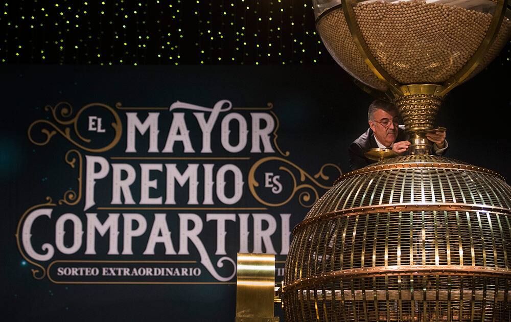 A worker opens a trap-door in a giant drum to let the balls bearing ticket numbers fall into a lower compartment before the start of Spain's Christmas lottery, in Madrid, Monday.