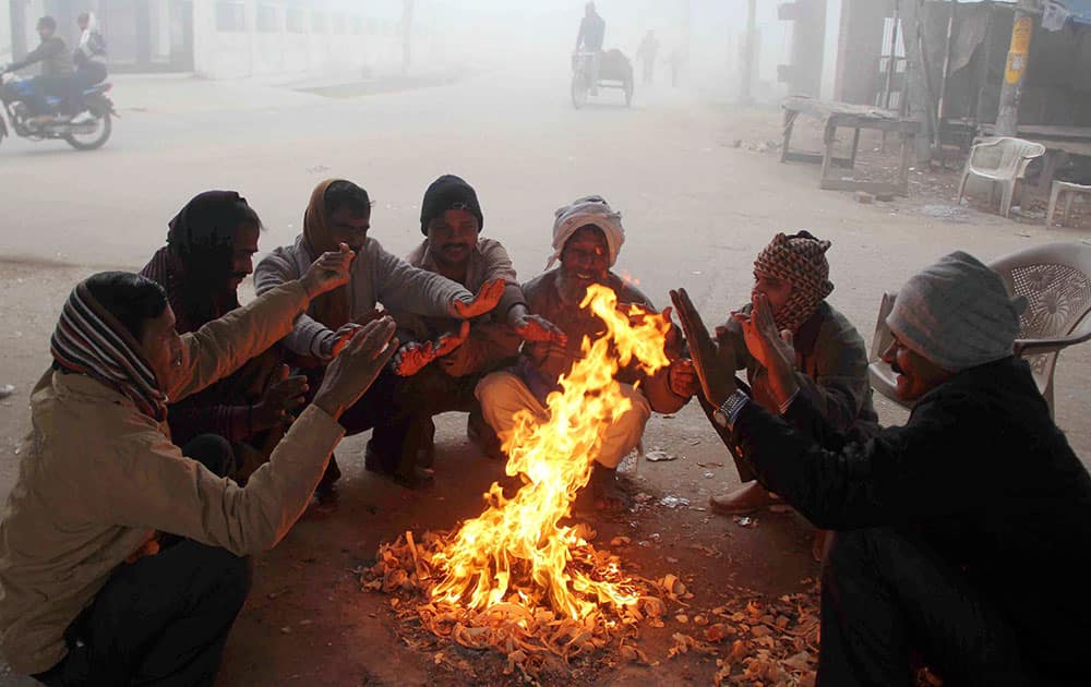 People sit around a bonfire to warm themselves during a chilly morning in Allahabad.