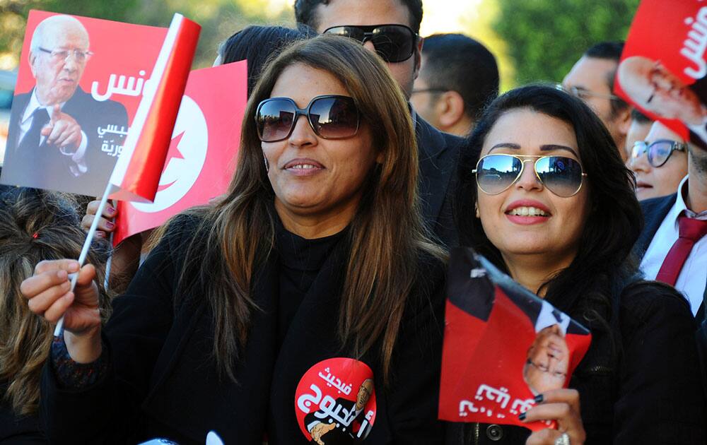 Supporters of Beji Caid Essebsi wave campaign posters or flags outside his party headquarters, after he was elected Tunisian President, in Tunis.