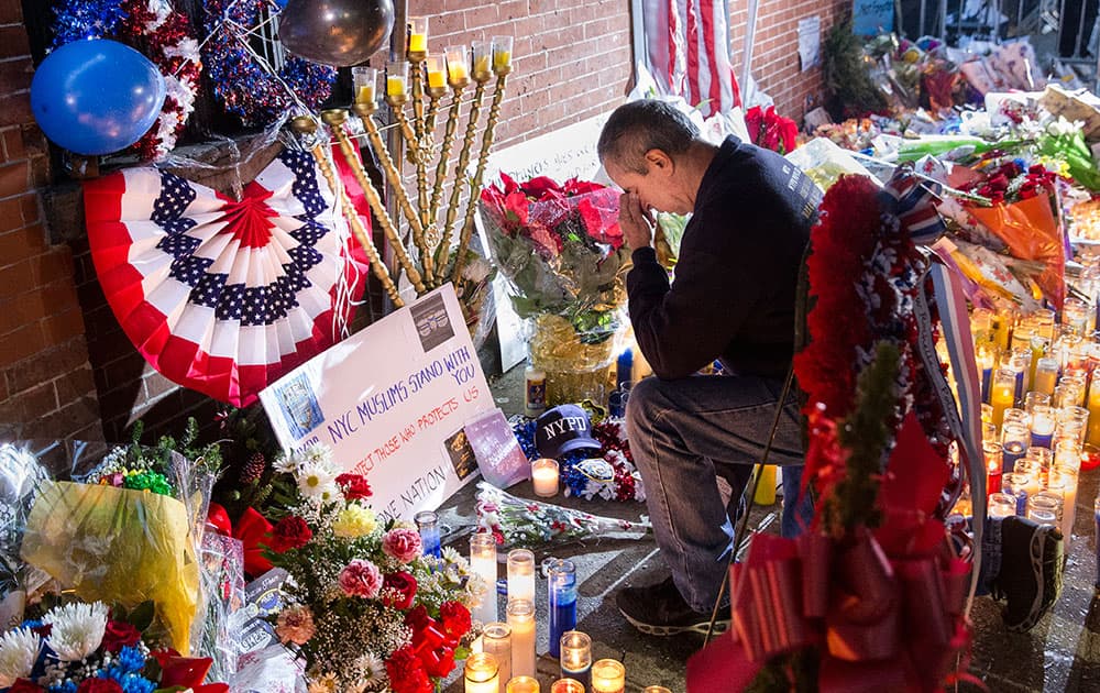 Retired police officer Henry Lallave kneels at a makeshift memorial near the site where NYPD officers Rafael Ramos and Wenjian Liu were murdered in the Brooklyn borough of New York.