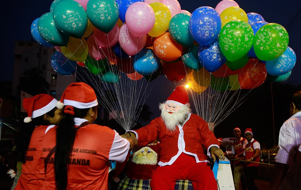 A man dressed as Santa Claus distributes candy, seated on a horse cart during a Christmas carnival in Mumbai.