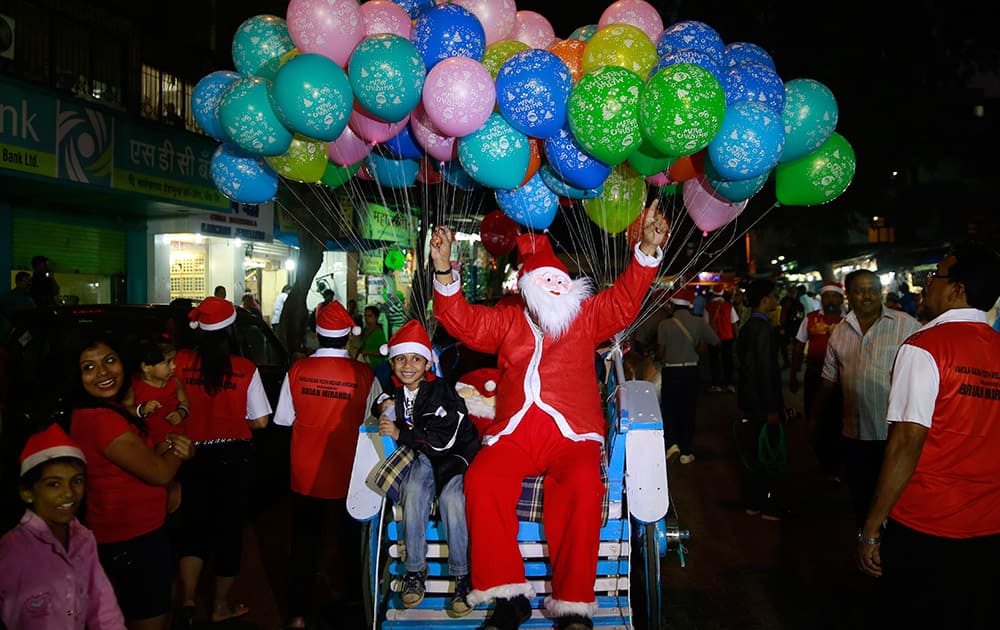 A man dressed as Santa Claus sits on a horse cart with a child during a Christmas carnival in Mumbai.