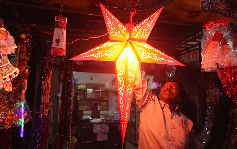 Vendor hangs a decorative star as he displays it to a customer ahead of Christmas in Ahmedabad.