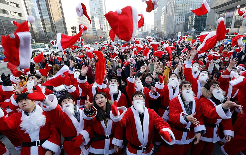 Volunteers clad in Santa Claus costumes throw their hats in the air as they gather to deliver gifts for the poor in downtown Seoul, South Korea.