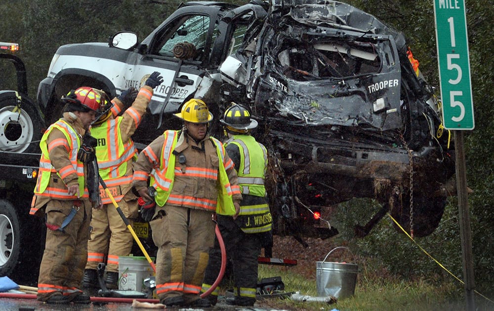Firefighters clear away debris from the site of an accident where a Greyhound bus plowed into the back of a North Carolina Highway Patrolman's vehicle on the northbound side of I-40/85 near Mebane, N.C.