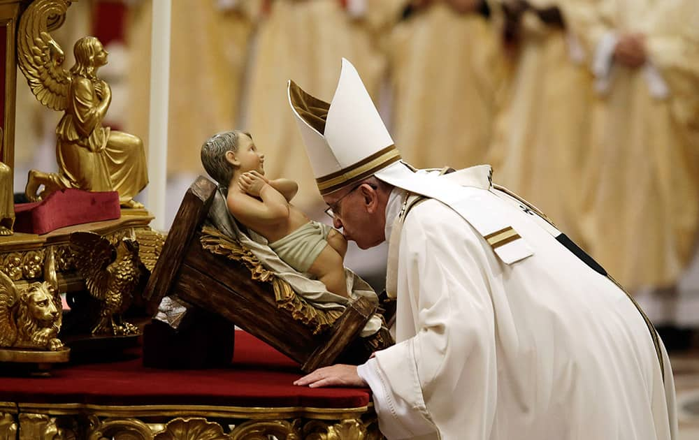 Pope Francis kisses a statue of Baby Jesus as he celebrates the Christmas Eve Mass in St. Peter's Basilica at the Vatican.