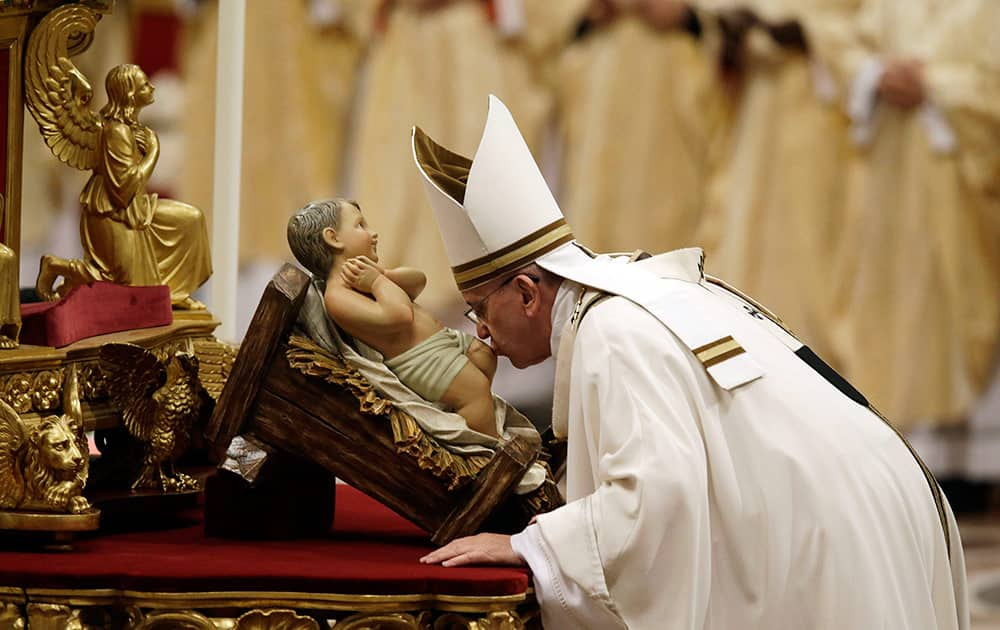 Pope Francis kisses a statue of Baby Jesus as he celebrates the Christmas Eve Mass in St. Peter's Basilica at the Vatican.