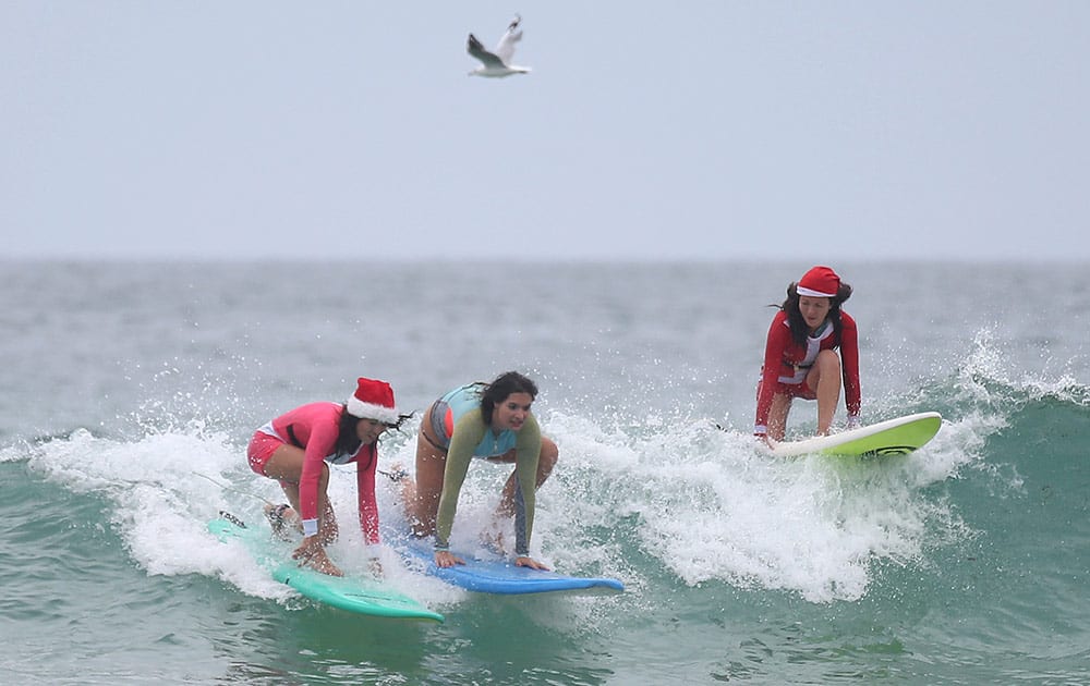 British travelers and twin sisters Dabriella, left, and Aprilla Quayle, right, ride the waves while celebrating Christmas Day at Bondi Beach in Sydney.