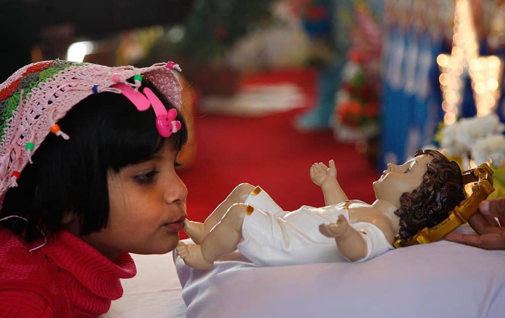 A girl kisses the feet of a baby Jesus statue after Christmas prayers at St. Mary's Garrison church, in Jammu.