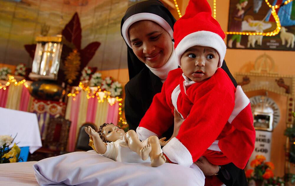 A nun shows a child in a Santa suit a statue of baby Jesus after Christmas prayers at St. Mary's Garrison church, in Jammu.