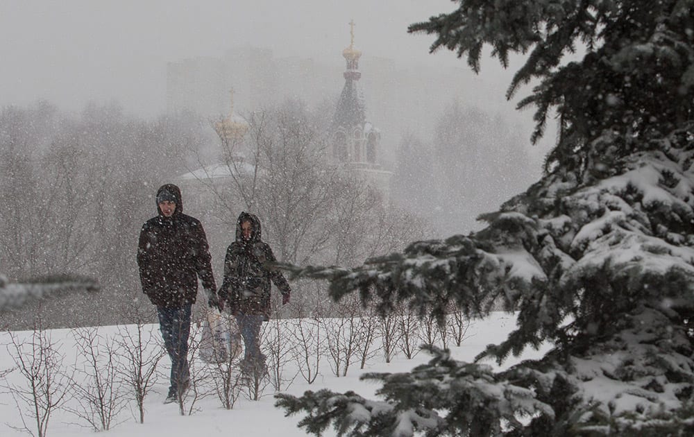 A couple walks in a park during a snowstorm in Moscow, Russia.