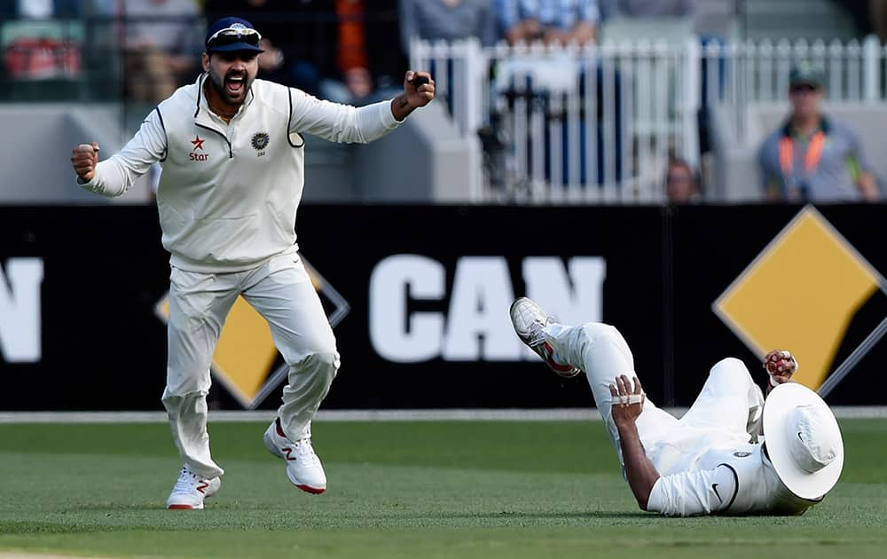 Murali Vijay, celebrates as teammate Shikhar Dhawan, catches out David Warner from Australia off the bowling of Umesh Yadavd during their play on day one of the third cricket test in Melbourne.