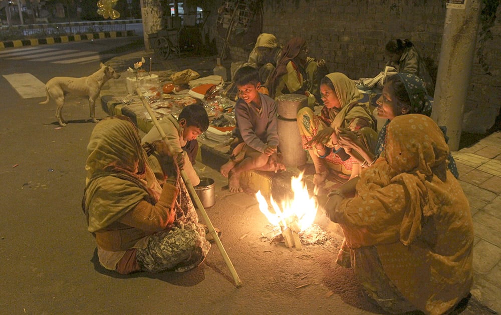 Family living on a roadside keeps themselves warm by sitting around a bonfire in Ahmedabad.