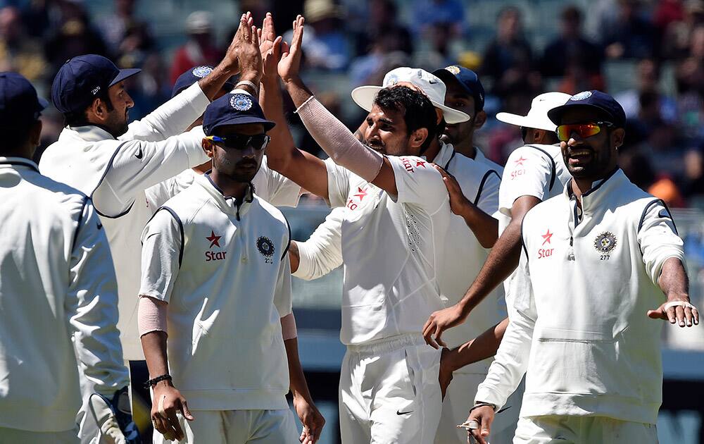 Indian players celebrate the wicket of Australia's Shaun Marsh off the bowling of Mohammed Shami during their play on day one of the third cricket test in Melbourne, Australia.