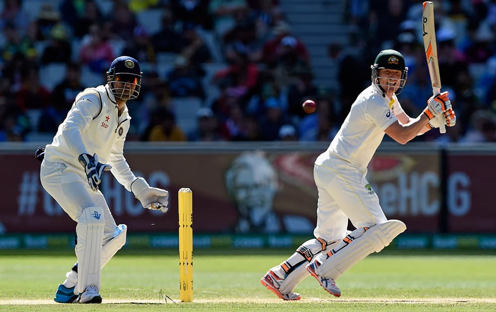 Australia's Brad Haddin, hits a cut shot as India's MS Dhoni, watches on during their play on day one of the third cricket test in Melbourne, Australia.