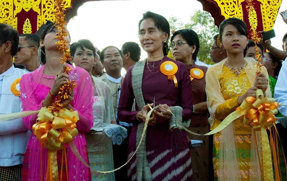 Myanmar Opposition Leader Aung San Suu Kyi, cuts a ribbon as she attends a ceremony to mark the 50th anniversary Kaw-Hmu township, her constituency for a parliament seat, in Yangon, Myanmar.