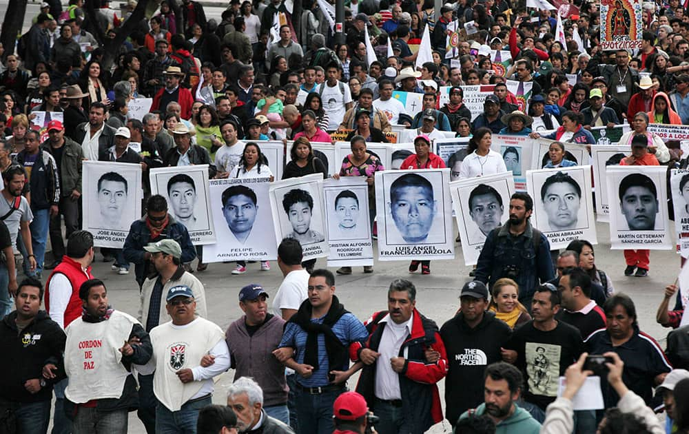 Relatives of the 43 missing students from the Isidro Burgos rural teachers college march holding pictures of their missing loved ones during a protest in Mexico City.