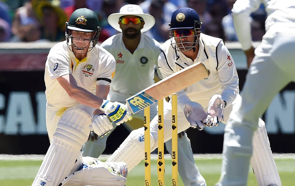 Australia's Steve Smith, attempts to sweep the ball in front of wicketkeeper MS Dhoni, on the second day of their cricket test match in Melbourne, Australia.