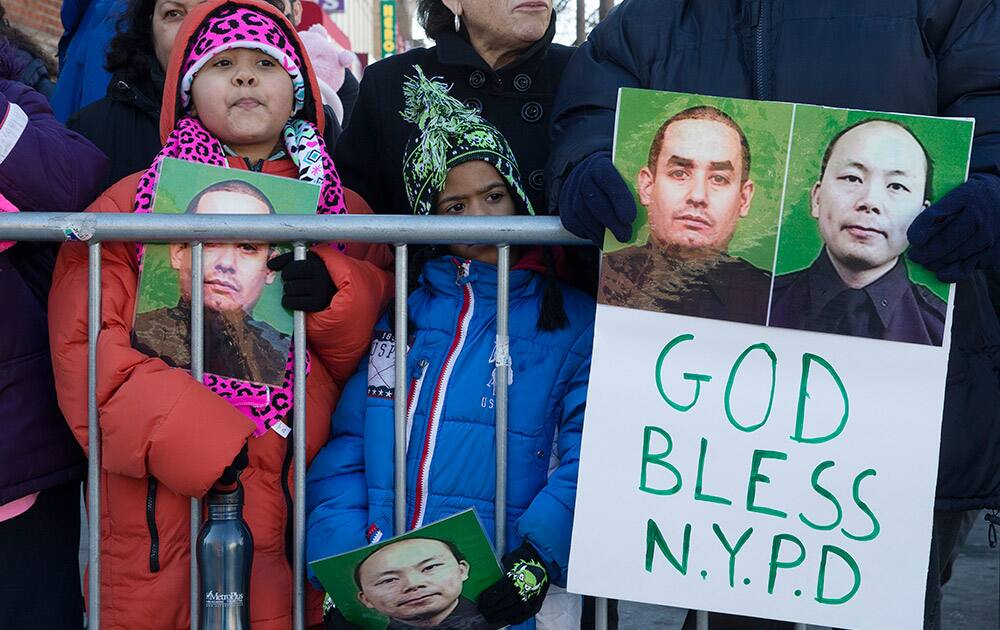 Mourners stand at a barricade near Christ Tabernacle Church, in the Glendale section of Queens, as the casket of New York Police Department officer Rafael Ramos arrives for his wake, in New York.