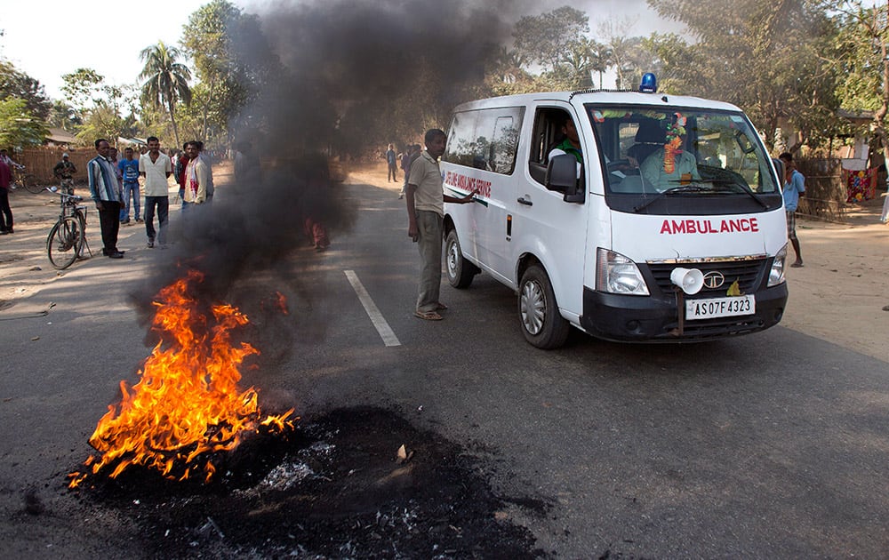 Tribal people allow an ambulance to go as they burn tires to block a national highway during a twelve hour general strike in Biswanath Chariali in Indian northeastern state of Assam.