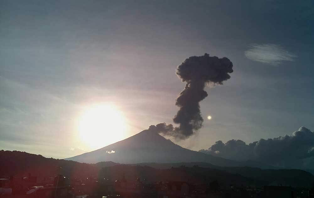 The sun sets as a plume of gas, ash and steam rises from the crater of the Popocatepetl volcano, seen from the town of San Nicolas de los Ranchos, Mexico.