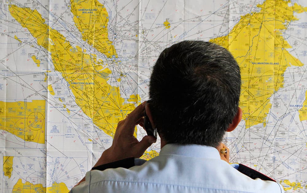 An airport official checks a map of Indonesia at the crisis center set up by local authority for the missing AirAsia flight QZ8501, at Juanda International Airport in Surabaya, East Java, Indonesia.