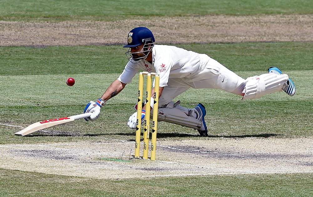 India's Virat Kohli dives back to his crease to avoid being run out on the third day of their cricket test match against Australia in Melbourne, Australia.