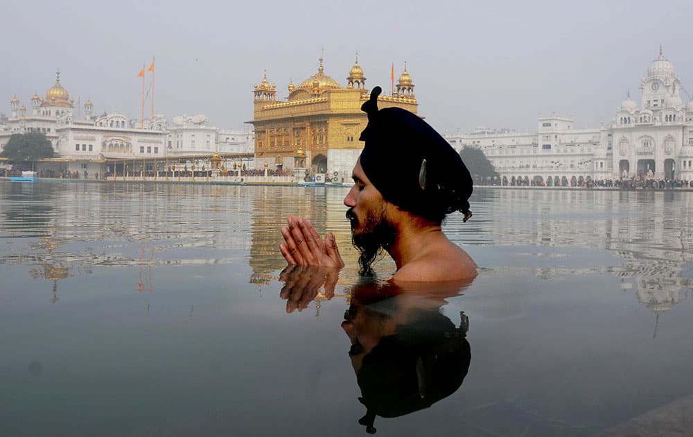 A Sikh devotee takes dip in the holy sarovar at the Sikh Shrine on the occasion of birth anniversary of Guru Gobind Singh, in Golden Temple.