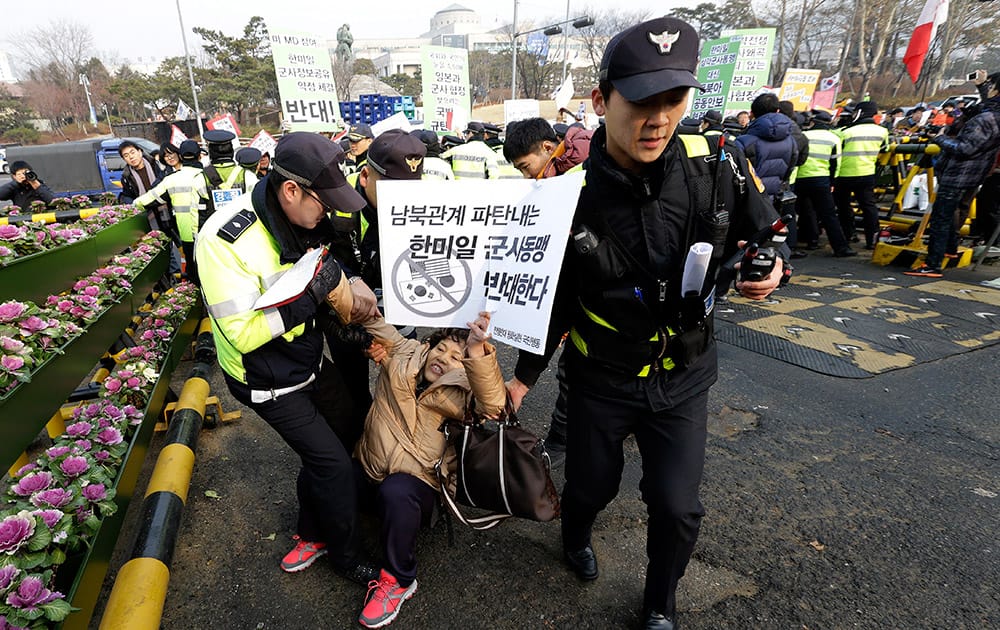 Police officers detain a protester during a rally against the joint intelligence-sharing pact by South Korea, the U.S. and Japan, in front of the Defense Ministry in Seoul, South Korea.