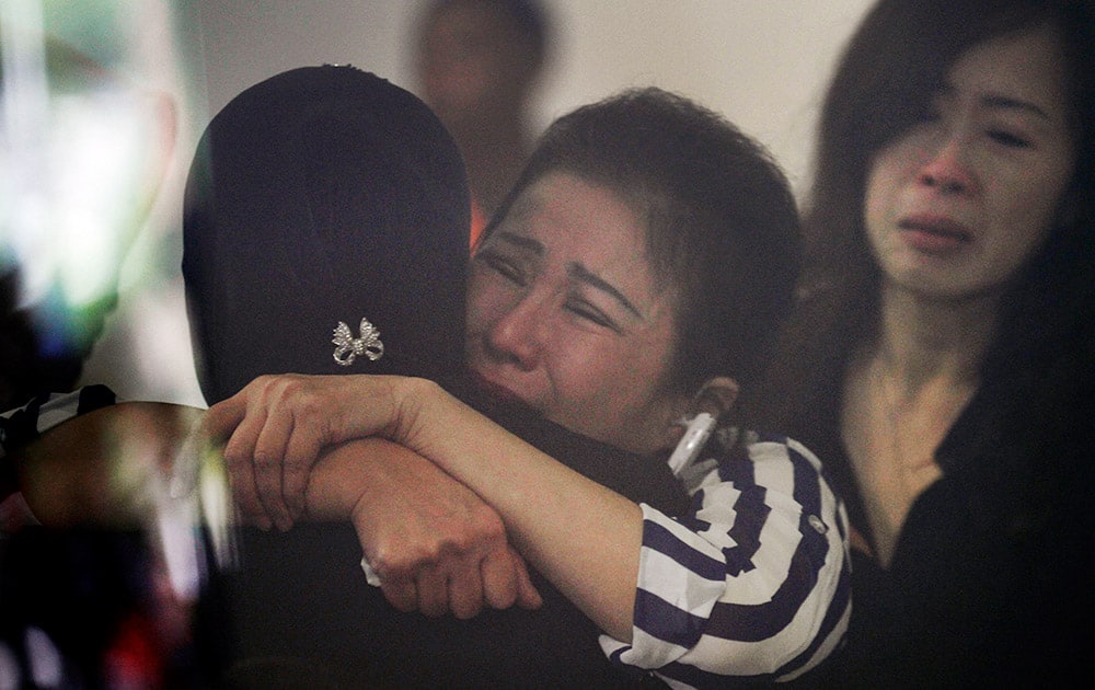 Relatives and next-of-kin of passengers on the AirAsia flight QZ8501 comfort each other as they wait for the latest news on the search of the missing jetliner at Juanda International Airport in Surabaya, East Java, Indonesia.