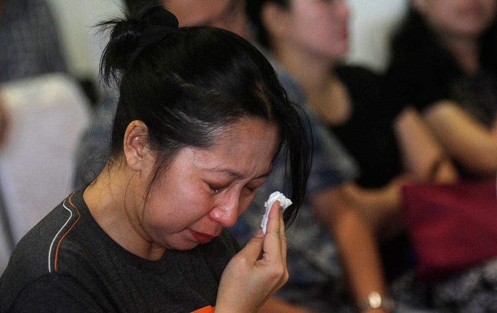 One of relatives and next-of-kin of passengers on the AirAsia flight QZ8501 wipes tears as she awaits the latest news on the search of the missing jetliner at Juanda International Airport in Surabaya, East Java, Indonesia.