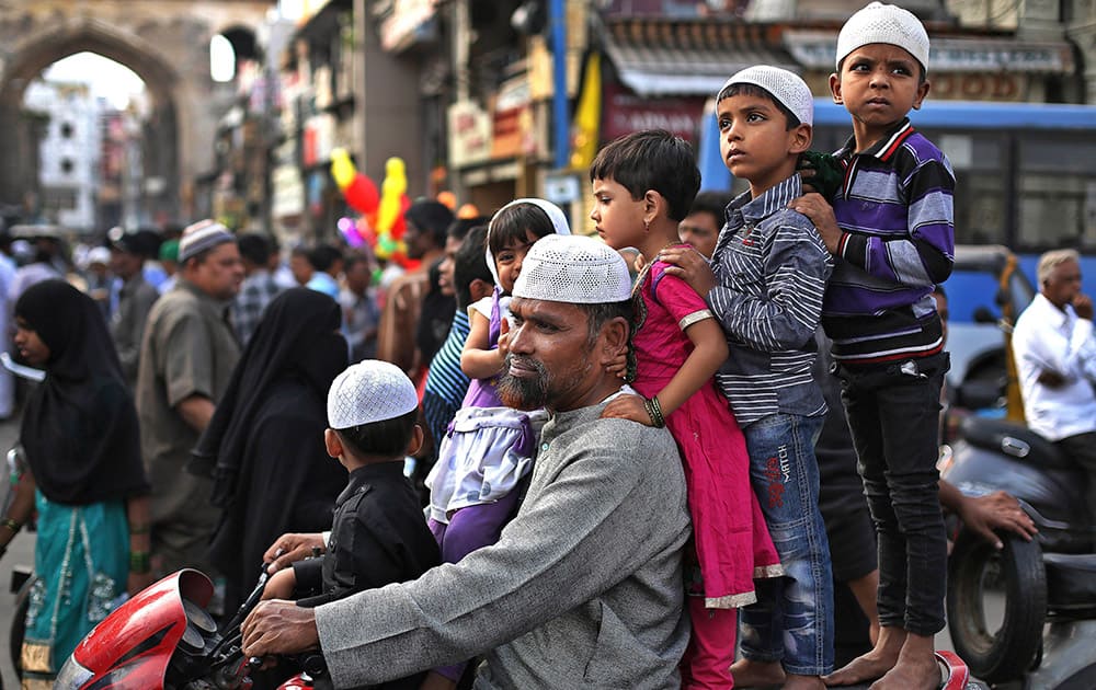 MUSLIM CHILDREN STAND ON A MOTORCYCLE AND WATCH AN ASHOURA PROCESSION IN HYDERABAD.