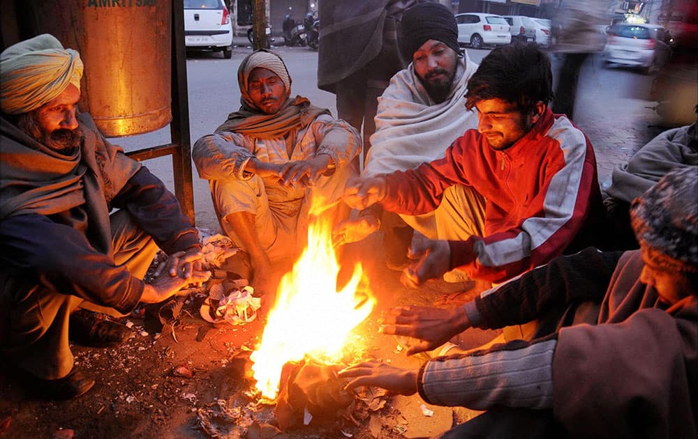 People warm themselves near a bonfire as temperatures dropped in Amritsar.