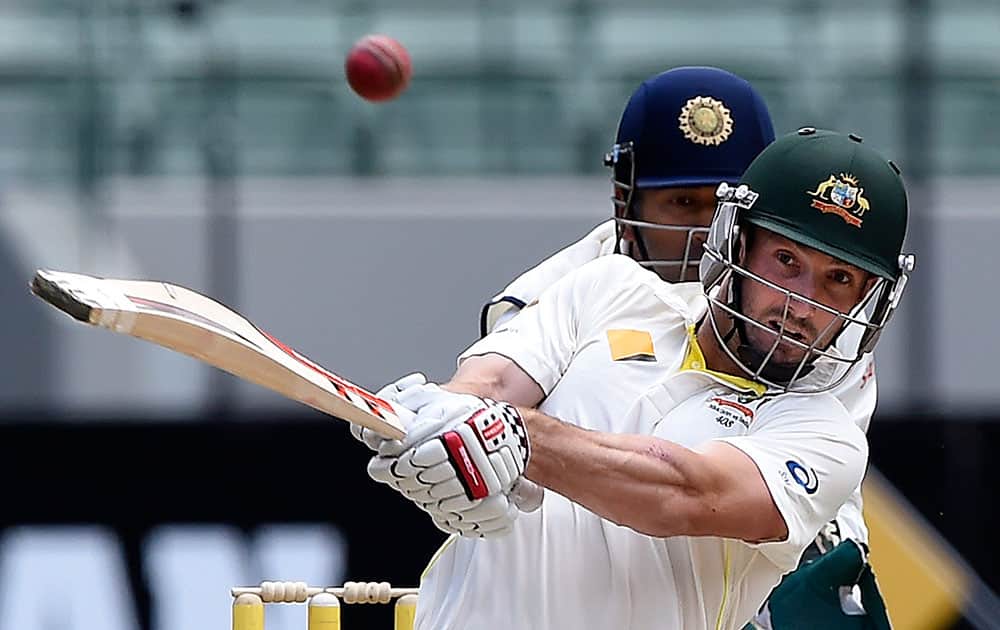 Australia's Shaun Marsh, right, drives the ball in front of India's MS Dhoni on the final day of their cricket test match in Melbourne, Australia.