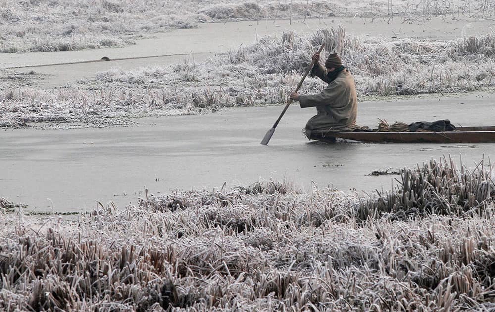 A Kashmiri boat man makes his way through the frozen surface of water of a Lake on a cold and foggy morning in Srinagar.