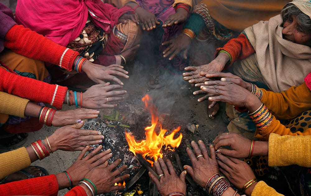 Passengers warm themselves around a fire as they wait for their train to arrive on a cold morning, in Allahabad.