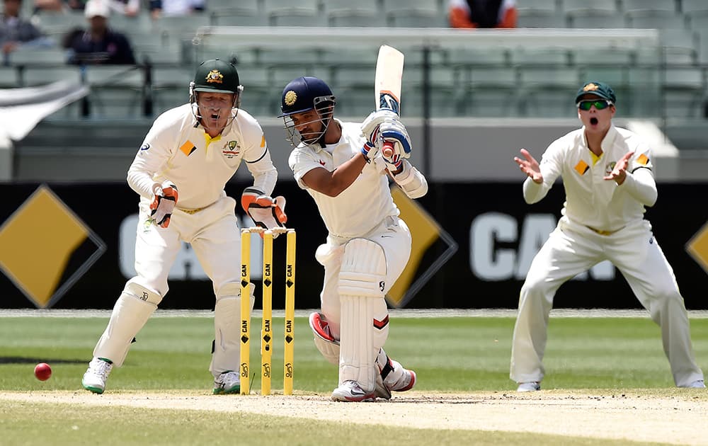 Ajinkya Rahane, drives the ball in front of Australia's Brad Haddin and Steve Smith on the final day of their cricket test match in Melbourne, Australia.