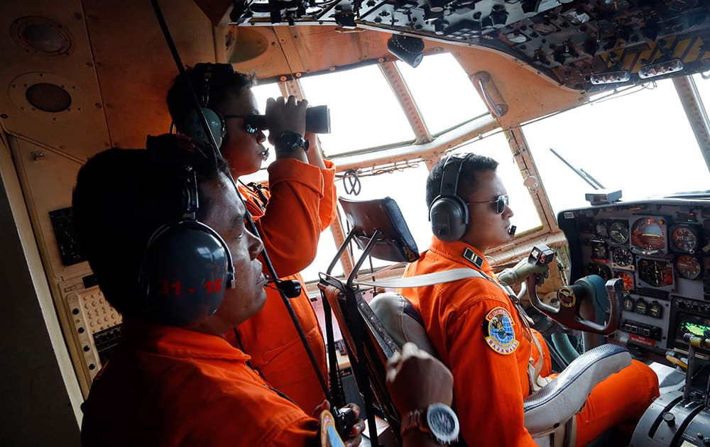 Crew of Indonesian Air Force C-130 airplane of the 31st Air Squadron scan the horizon during a search operation for the missing AirAsia flight 8501 jetliner over the waters of Karimata Strait in Indonesia.