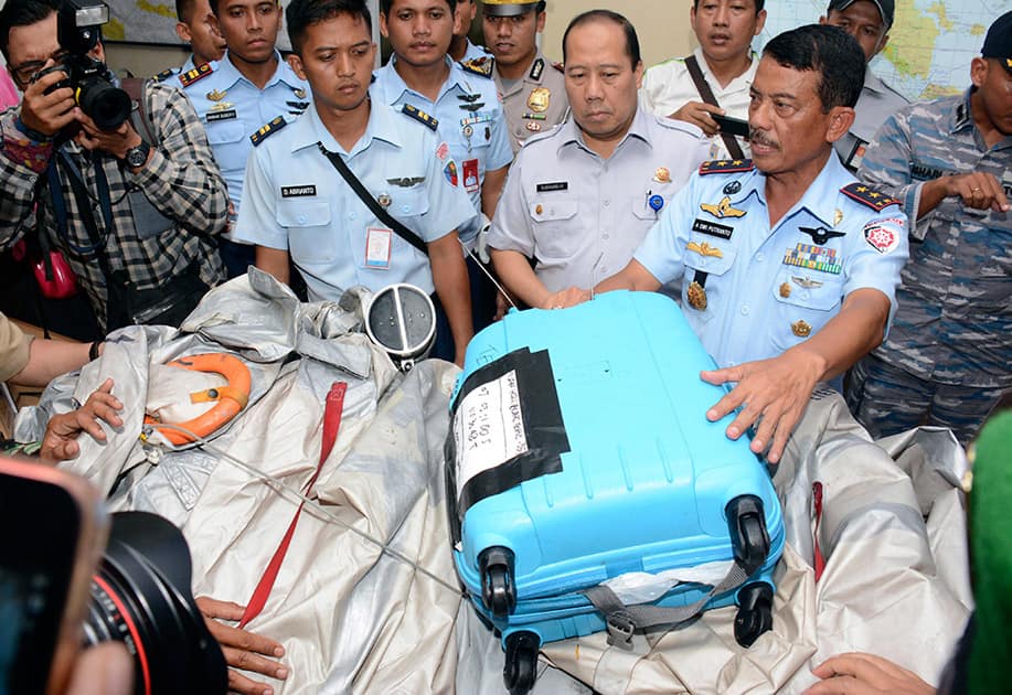 Commander of 1st Indonesian Air Force Operational Command Rear Marshall Dwi Putranto, shows airplane parts and a suitcase found floating on the water near the site where AirAsia Flight 8501 disappeared, during a press conference at the airbase in Pangkalan Bun, Central Borneo, Indonesia.