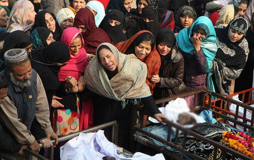 Pakistani family members mourn for victims of a fire in Lahore, Pakistan.